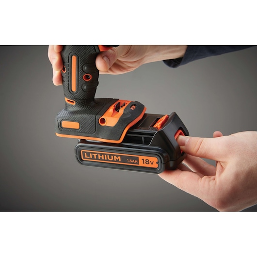 Close-up view of hands attaching an 18V 1.5Ah lithium battery to a BLACK+DECKER cordless power tool.