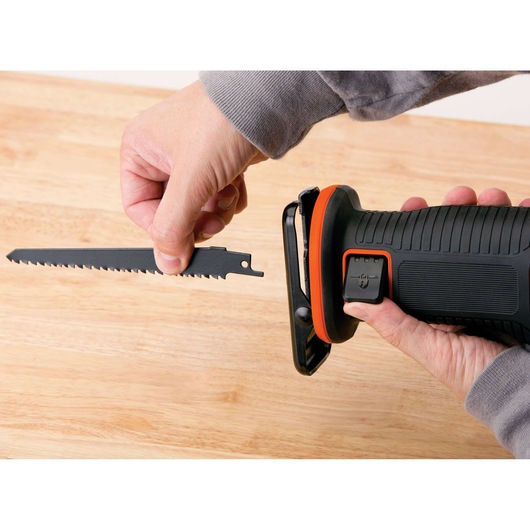 BLACKDECKER BDCR18N reciprocating saw close-up with hands changing blade on light wood surface.