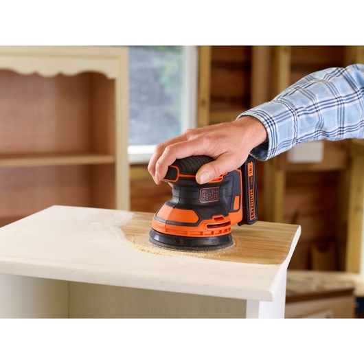 BLACKDECKER BDCROS18N cordless random orbital sander being used on wooden furniture.