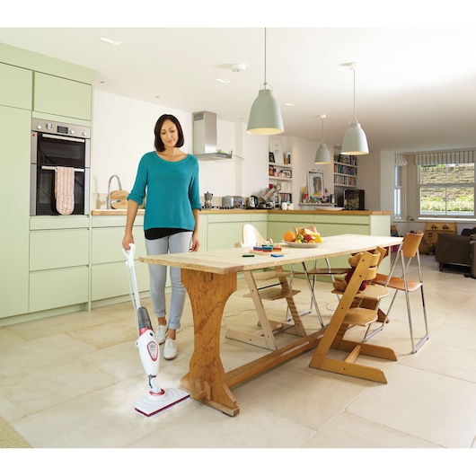 BLACKDECKER BDS1616R steam mop used on tile floor in modern kitchen beside wooden dining table.
