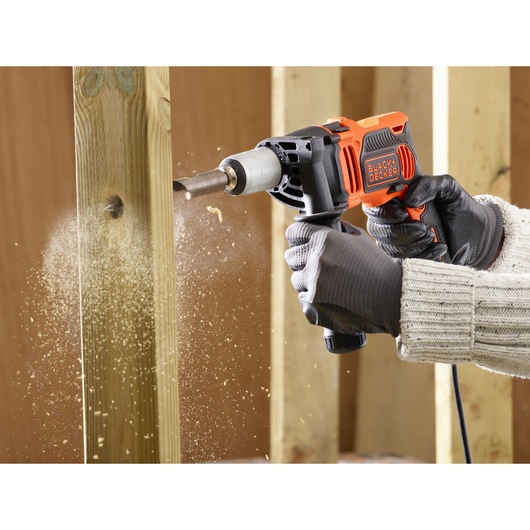 BLACKDECKER BEH850 hammer drill in use drilling through wood, close-up with wood shavings flying.
