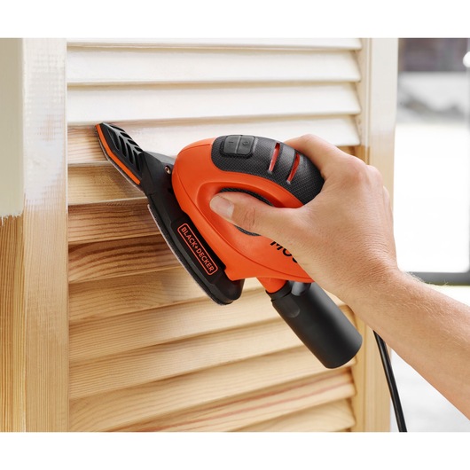 BLACK+DECKER BEW230BCES detail sander in use on wooden shutters, close-up angle.