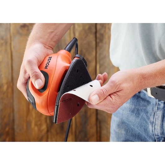 BLACKDECKER BEW230K mouse sander with sanding sheet being attached, handheld, photography close-up.