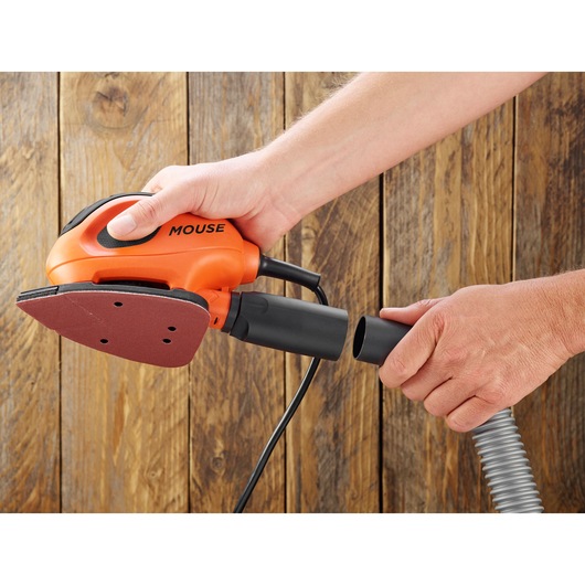BLACKDECKER BEW230 mouse sander with vacuum hose, angled view, held by hands, wooden background.