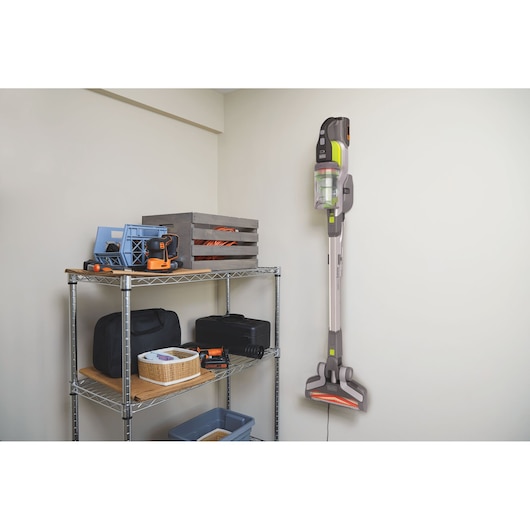 BLACKDECKER BHFEV362DA vacuum cleaner mounted on wall in storage room next to metal shelving with tools and boxes.