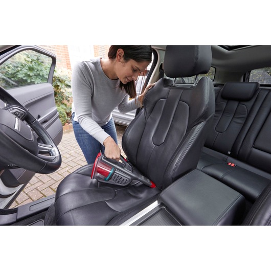 BLACKDECKER BHHV315J handheld vacuum cleaning black car seat upholstery, indoor photography.