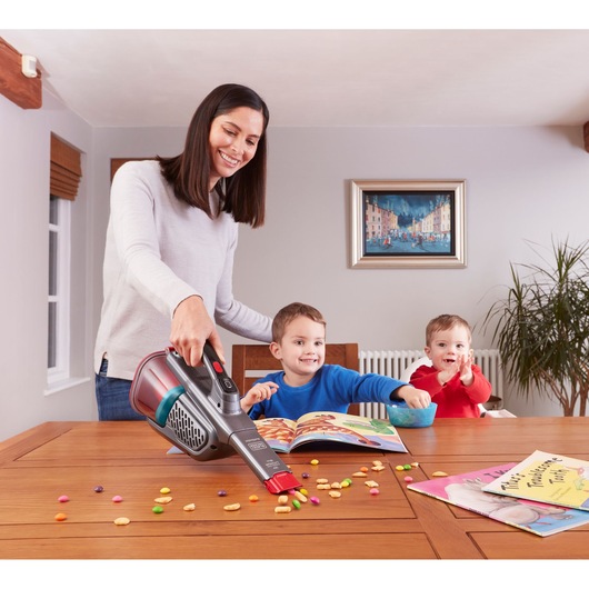 BLACKDECKER BHHV315J handheld vacuum cleaning snacks from wooden table near children in dining room.