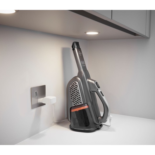 BLACKDECKER BHHV520JF handheld vacuum cleaner charging on a white countertop under cabinets.