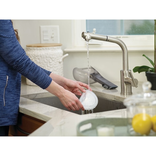 BLACKDECKER DVA315J handheld vacuum filter being rinsed under kitchen faucet, photography side angle