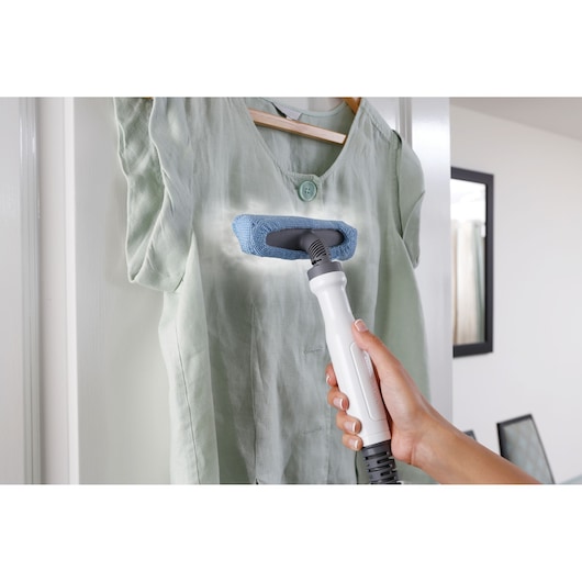 BLACKDECKER FSMH13101SM steam cleaner with blue cloth steamer attachment used on green shirt, close-up view.