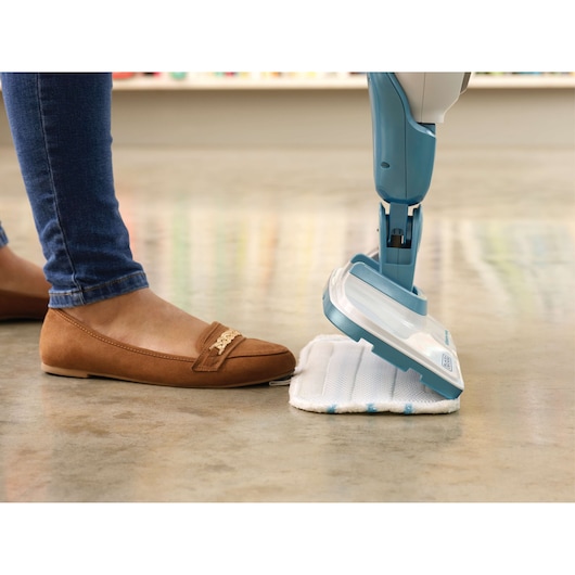 BLACKDECKER FSMH1351SM steam mop being operated by foot on a polished floor, close-up side view.