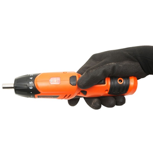 Photo of BLACKDECKER KC4815-IN orange cordless screwdriver held in hand, side angle, black glove visible.