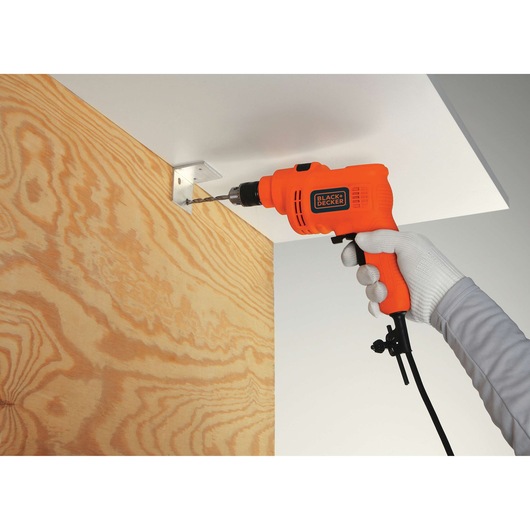 BLACK+DECKER KR5010V electric drill being used to drill into a metal bracket on a wood panel.