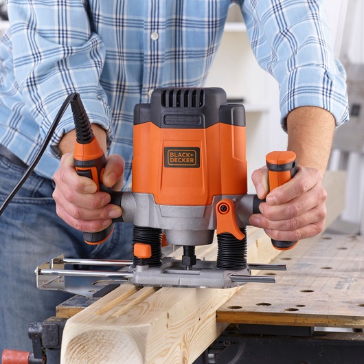 BLACKDECKER KW1200E woodworking router in use on a wooden plank, orange and black design.