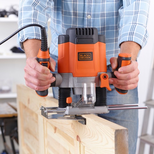 Photo of BLACK+DECKER KW1200E woodworking router used on a wooden board, close-up view.
