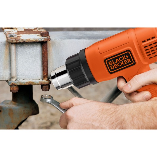 BLACK+DECKER KX1650 heat gun in use on a rusted metal bolt with wrench, close-up view.