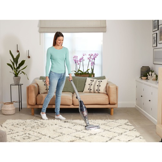 BLACKDECKER SVB520JW stick vacuum cleaner in use on a patterned rug in a modern living room.