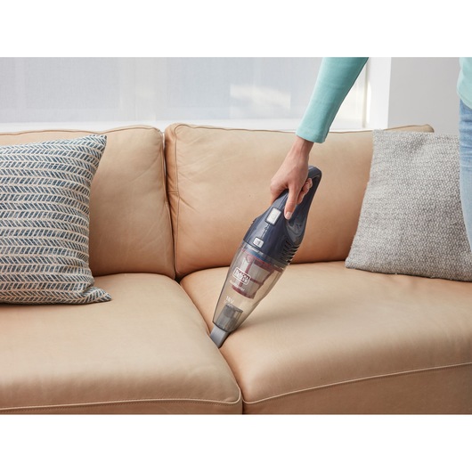 BLACKDECKER SVB520JW handheld vacuum cleaning beige sofa with patterned cushions