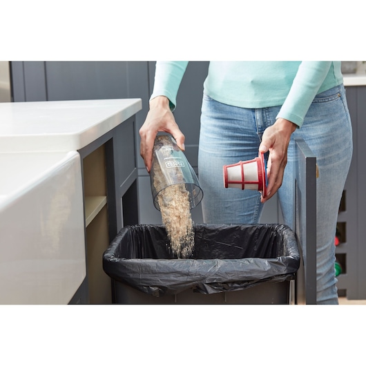 Photo of BLACKDECKER SVB520JW vacuum dustbin being emptied into a kitchen trash can.
