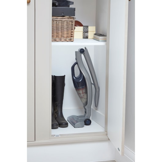 BLACKDECKER SVB520JW cordless stick vacuum stored upright in a white closet next to black boots.